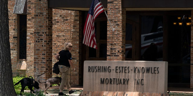 A woman with two comfort dogs enters a mortuary during a visitation for Maite Yuleana Rodriguez, one of the victims killed in last week's elementary school shooting in Uvalde, Texas, Monday, May 30, 2022.