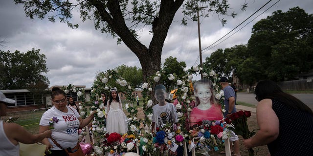 Dorina Davila, left, from San Antonio, places flowers at a memorial outside Robb Elementary School in Uvalde, Texas, Monday, May 30, 2022.