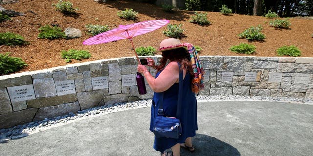 Karla Hailer, a fifth-grade teacher from Scituate, Mass., takes a video on July 19, 2017, where a memorial stands at the site in Salem, Mass., where five women were hanged as witches more than three centuries years earlier. Massachusetts lawmakers on Thursday, May 26, 2022, formally exonerated Elizabeth Johnson Jr., clearing her name 329 years after she was convicted of witchcraft in 1693 at the height of the Salem Witch Trials.