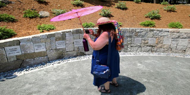 Karla Hailer, a fifth-grade teacher from Scituate, Mass., takes a video on July 19, 2017, where a memorial stands at the site in Salem, Mass., where five women were hanged as witches more than three centuries years earlier. Massachusetts lawmakers on Thursday, May 26, 2022, formally exonerated Elizabeth Johnson Jr., clearing her name 329 years after she was convicted of witchcraft in 1693 at the height of the Salem Witch Trials.