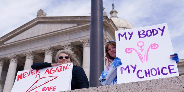 Dani Thayer, left, and Marina Lanae, right, both of Tulsa, Oklahoma, hold pro-choice signs at the state Capitol, April 13, 2022, in Oklahoma City.