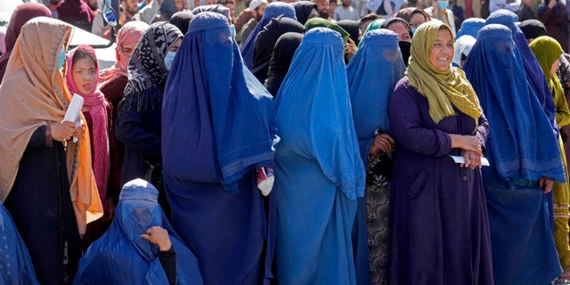Women wait to receive food distributed by a humanitarian aid group, in Kabul, Afghanistan in April 2022.