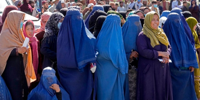 Afghan women wait to receive food rations distributed by a Saudi humanitarian aid group, in Kabul, Afghanistan, Monday, April 25, 2022.