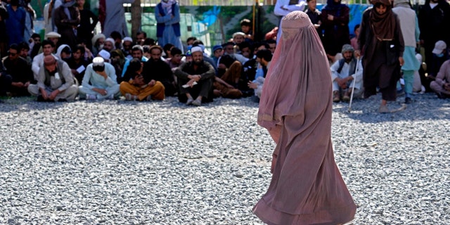 An Afghan woman waits to receive food rations distributed by a Saudi humanitarian aid group, in Kabul, Afghanistan, Monday, April 25, 2022. 