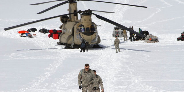 FILE - Capt. Corey Wheeler, front, commander of B Company, 1st Battalion, 52nd Aviation Regiment at Fort Wainwright, Alaska, walks away from a Chinook helicopter that landed on the glacier near Denali, April 24, 2016, on the Kahiltna Glacier in Alaska.