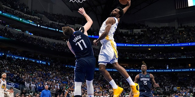 Golden State Warriors forward Andrew Wiggins (22) dunks the ball over Dallas Mavericks guard Luka Doncic (77) during the second half of Game 3 of the NBA basketball playoffs Western Conference finals, Sondag, Mei 22, 2022, in Dallas.