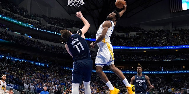 Golden State Warriors forward Andrew Wiggins (22) dunks the ball over Dallas Mavericks guard Luka Doncic (77) during the second half of Game 3 of the NBA basketball playoffs Western Conference finals, Sunday, May 22, 2022, in Dallas.