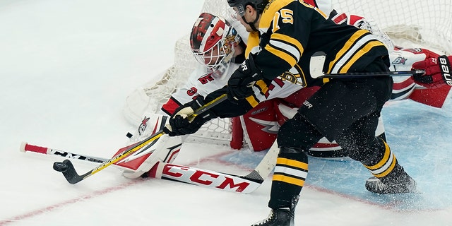Carolina Hurricanes' Antti Raanta and Bruins' Connor Clifton vie for control of the puck in the first-round playoff series, Sunday, May 8, 2022, in Boston.