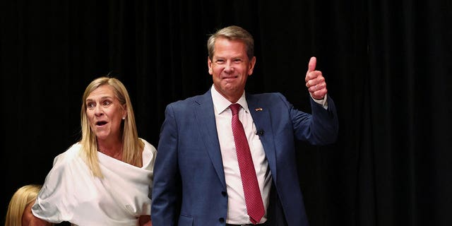Georgia Gov. Brian Kemp walks on stage with his wife Marty Kemp to speak after winning the Republican primary during his primary election watch party in Atlanta on May 24, 2022.