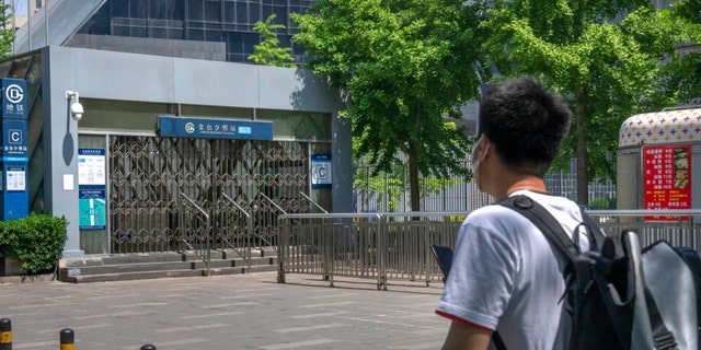 رجل يرتدي قناعًا للوجه ينظر إلى مخرج مغلق لمحطة مترو أنفاق في بكين ، الأربعاء 4 مايو 2022.