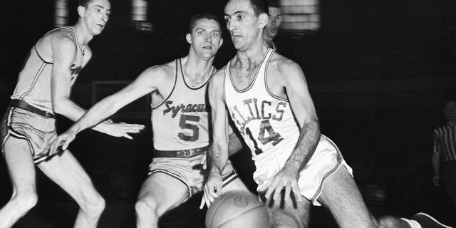 Bob Cousy (14) of the Boston Celtics moves into score through Syracuse Men, Red Rocha (izquierda) and Paul Seymour (5), in the second quarter of the playoffs game at the Boston Arena.
