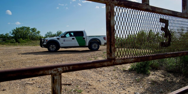 A U.S. Border Patrol agent sits in a truck on a road outside a ranch gate near Carrizzo Springs, Texas, U.S.