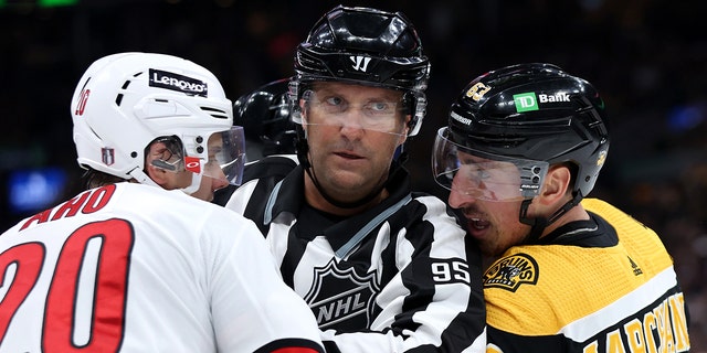 Linesman Jonny Murray separates Brad Marchand of the Boston Bruins, right, and Sebastian Aho (20) of the Carolina Hurricanes during the second period of Game 3 of the first round of the 2022 Stanley Cup playoffs at TD Garden on May 6, 2022 in Boston.
