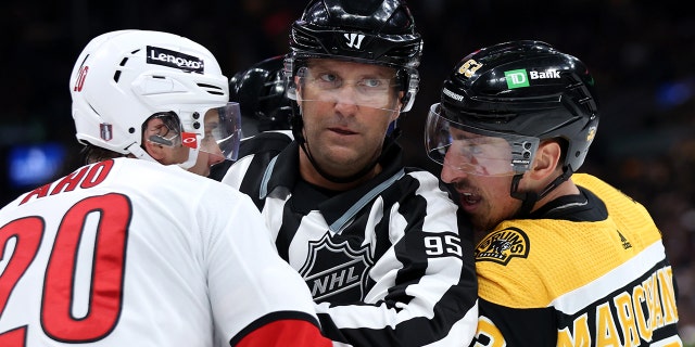 Linesman Jonny Murray separates Brad Marchand of the Boston Bruins, right, and Sebastian Aho (20) of the Carolina Hurricanes during the second period of Game 3 of the first round of the 2022 Stanley Cup playoffs at TD Garden on May 6, 2022 in Boston.