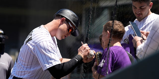 Colorado Rockies catcher Brian Serven signs an autograph for a fan before making his major league debut, Wednesday, May 18, 2022, in Denver.