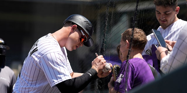 Colorado Rockies catcher Brian Serven signs an autograph for a fan before making his major league debut, Wednesday, May 18, 2022, in Denver.