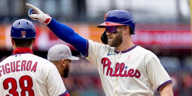 Philadelphia Phillies' Bryce Harper (3) gestures from first base after hitting an RBI single during the third inning of the first game of a double header against the New York Mets, 星期日, 可能 8, 2022, 在费城.