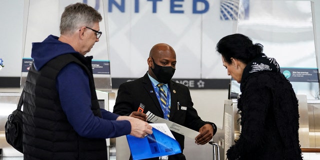 FILE: A United Airlines worker assists travelers after the Biden administration announced it would no longer enforce a U.S. coronavirus disease (COVID-19) mask mandate on public transportation, at Ronald Reagan Washington National Airport in Arlington, Virginia, U.S.