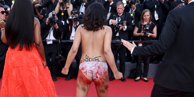 Um manifestante que estava usando pintura corporal em sua frente que dizia "Pare de nos estuprar" na cor da bandeira ucraniana aparece na estreia do filme 'Três mil anos de saudade' no 75º festival internacional de cinema, Cannes, sul da França, sexta-feira, 20 de maio de 2022.
