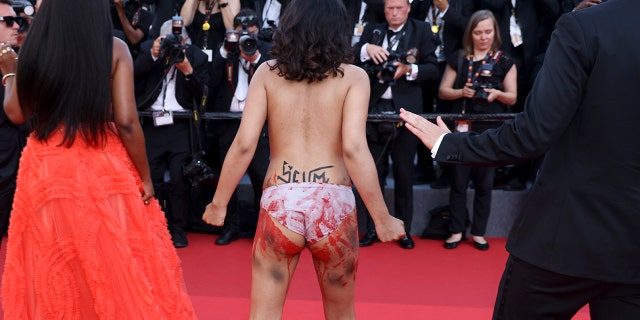 A protestor that was wearing body paint on her front that read "Stop Raping Us" in the color of the Ukrainian flag appears at the premiere of the film 'Three Thousand Years of Longing' at the 75th international film festival, Cannes, southern France, Friday, May 20, 2022.