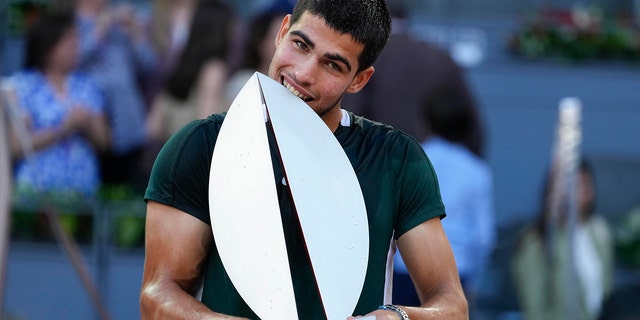 Carlos Alcaraz, of Spain, bites the trophy after winning the final match against Alexander Zverev, of Germany, at the Mutua Madrid Open tennis tournament in Madrid, Spagna, Domenica, Maggio 8, 2022. 