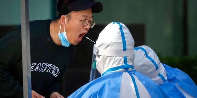 A worker wearing a protective suit swabs a man’s throat for a COVID-19 test on the third consecutive day of mass coronavirus testing in Beijing, Thursday, May 5, 2022. Hong Kong on Thursday reopened beaches and pools in a relaxation of COVID-19 restrictions, while China’s capital Beijing began easing quarantine rules for arrivals from overseas. 