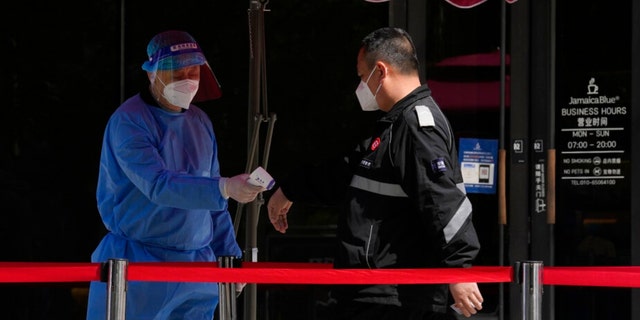 A worker takes the temperature of a resident lining up for mass COVID test on Wednesday, May 11, 2022, in Beijing.