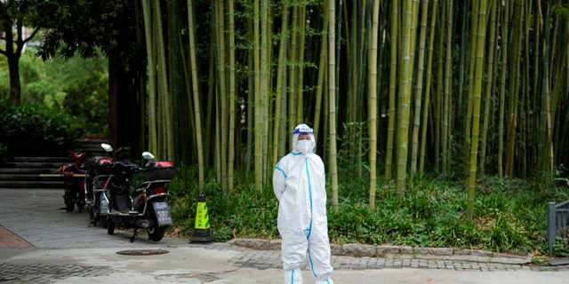 Une femme en tenue de protection se tient dans une rue pendant le verrouillage, au milieu de la pandémie de maladie à coronavirus (COVID-19), à Shanghai, en Chine, le 26 mai 2022. 