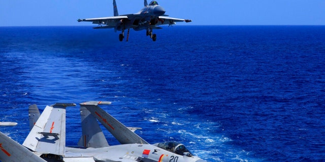 In this photo released on December 31, 2021 by Xinhua News Agency, an undated photo shows a carrier-based J-15 fighter jet preparing to land on the Chinese Navy's Liaoning aircraft carrier during 'combat training on the high seas. China is holding military exercises in the disputed South China Sea to coincide with US President Joe Biden's visits to South Korea and Japan, which are largely focused on countering the threat perceived from China. 