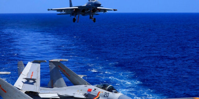 In this photo released Dec. 31, 2021 by Xinhua News Agency, an undated photo shows a carrier-based J-15 fighter jet preparing to land on the Chinese navy's Liaoning aircraft-carrier during open-sea combat training. 