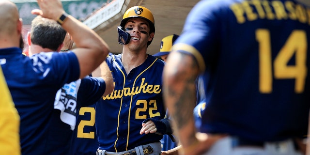 Milwaukee Brewers' Christian Yelich high-fives teammates in the dugout after scoring a run against the Reds in Cincinnati, Wednesday, May 11, 2022.