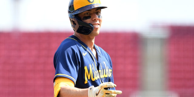 Christian Yelich of the Milwaukee Brewers signals to the dugout after hitting a triple against the Reds at Great American Ball Park on May 11, 2022, in Cincinnati, Ohio.