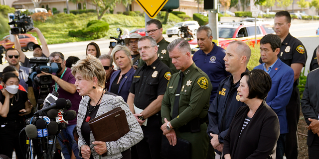 Laguna Woods Mayor Carol Moore, front left at podium, and Orange County Board of Supervisor, Lisa Barlett, right, surrounded by law enforcement officers, hold a press conference outside the grounds og Geneva Presbyterian Church in Laguna Woods, Calif., Sunday, May 15, 2022, after a fatal shooting. (AP Photo/Damian Dovarganes)