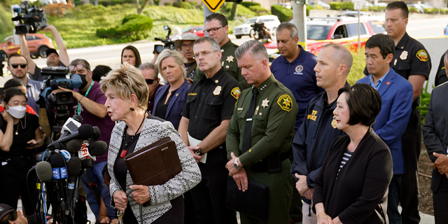 Laguna Woods Mayor Carol Moore, front left at podium, and Orange County Board of Supervisor, Lisa Barlett, right, surrounded by law enforcement officers, hold a press conference outside the grounds og Geneva Presbyterian Church in Laguna Woods, Calif., Sunday, May 15, 2022, after a fatal shooting. (AP Photo/Damian Dovarganes) 