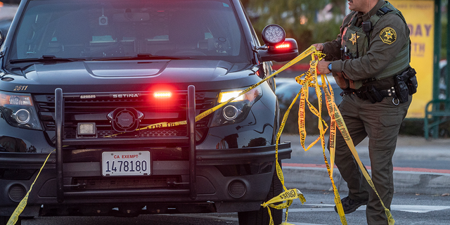 An Orange County Sheriff's deputy removes yellow tape from a vehicle outside the Geneva Presbyterian Church in Laguna Woods, Calif., Sunday, May 15, 2022, after a fatal shooting. 