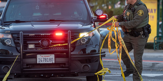 A Orange County Sheriff deputy removes yellow tape from a vehicle outside the Geneva Presbyterian Church in Laguna Woods, Calif., Sunday, May 15, 2022, after a fatal shooting. (AP Photo/Damian Dovarganes)