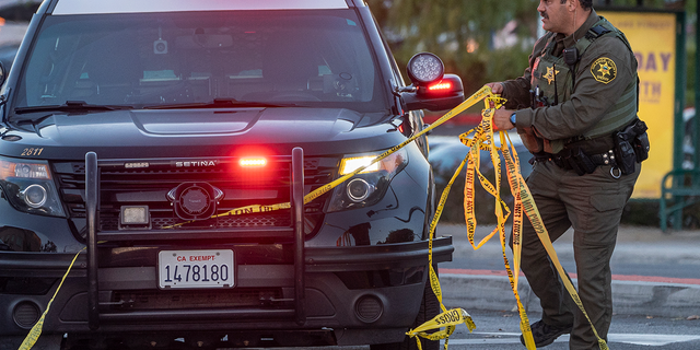 A Orange County Sheriff deputy removes yellow tape from a vehicle outside the Geneva Presbyterian Church in Laguna Woods, Calif., Sunday, May 15, 2022, after a fatal shooting. (AP Photo/Damian Dovarganes)