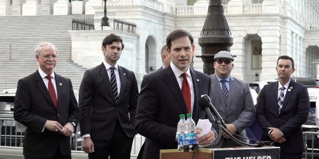 Senator Marco Rubio (Republican, Florida) speaks, while Senator John Ossoff (Democrat, Georgia), second from left, looks on.