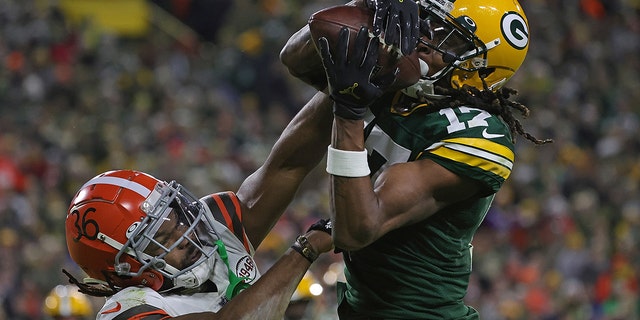 Davers Adams of the Packers catches a pass to a touchdown in front of MJ Stewart of the Cleveland Browns at Lambeau Field on December 25, 2021 in Green Bay, Wisconsin.