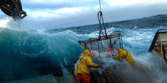 Deckhands hauling crab pot while water invades the boat.