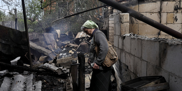 Vera Kosolupenko reage do lado de fora de sua casa destruída na vila de Bezruki, perto de Derhachy, na Ucrânia, em 14 de maio, após ser atingida por bombardeios russos.