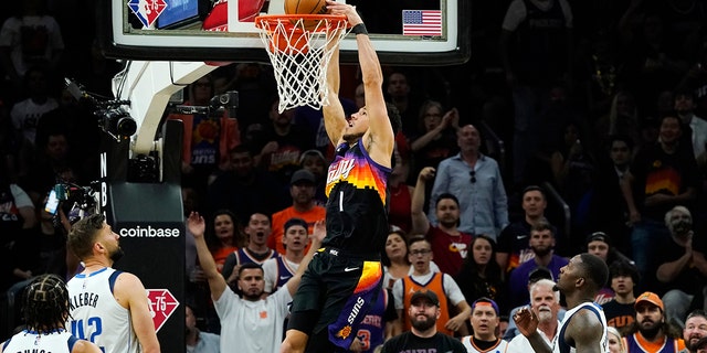 Phoenix Suns guard Devin Booker (1) dunks against Dallas Mavericks guard Jalen Brunson (13), Mavericks forwards Maxi Kleber (42) and Dorian Finney-Smith, 对, 上半场比赛 5 of an NBA basketball second-round playoff series Tuesday, 可能 10, 2022, 在凤凰城. 