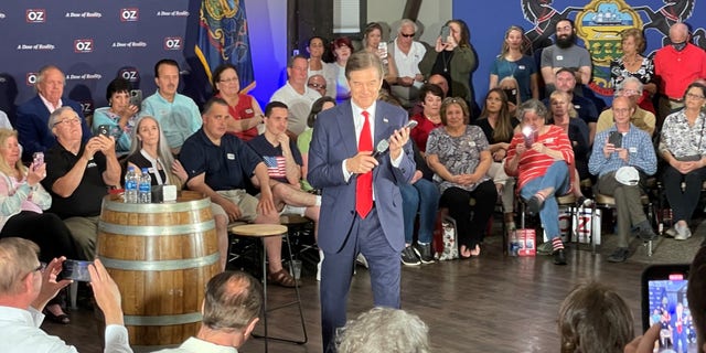 Republican Senate candidate Mehmet Oz listens as former President Donald Trump calls into Oz's primary eve rally in Blue Bell, Pennsylvania on May 16, 2022