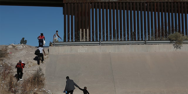 Haitian families cross the Rio Bravo River illegally to surrender to American authorities at Mexico's Ciudad Juarez border with El Paso, Texas, Dec.  23, 2021, in Ciudad Juarez, Mexico. 