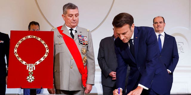French Presidential Chief of Military Staff Benoit Puga, center, left, stands next to French President Emmanuel Macron signing a document during his inauguration ceremony for a second term at the Élysée Palace in Paris on Saturday 7 May 2022. 