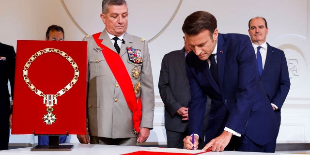 France's Military Chief of Staff to the presidency Benoit Puga, center, left, stands next to French President Emmanuel Macron signing a document during the ceremony of his inauguration for a second term at the Elysee palace, in Paris Saturday, May 7, 2022.