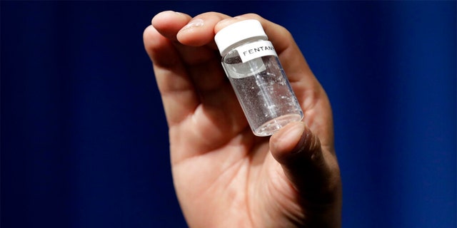 A reporter holds up an example of the amount of fentanyl that can be deadly at DEA Headquarters in Arlington, Virginia. 