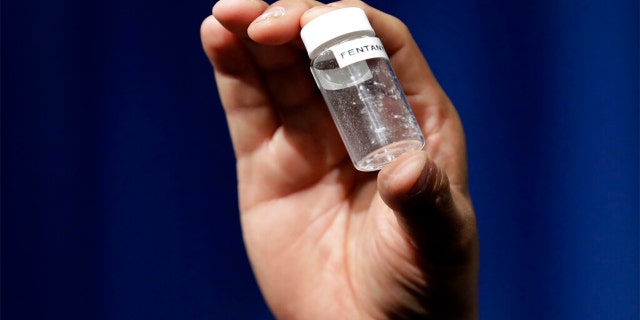 A reporter holds up a jar of fentanyl at DEA Headquarters in Arlington, Va., June 6, 2017. 