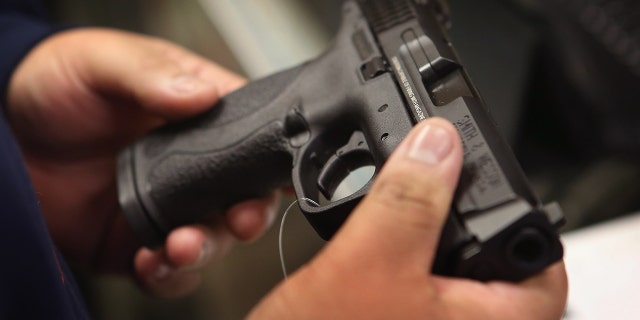 A customer shops for a pistol at a sporting goods store.