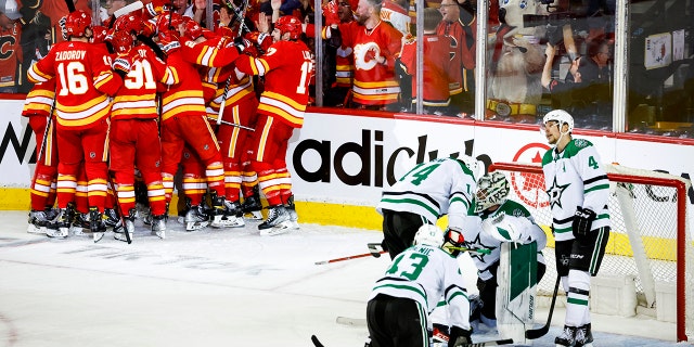 Dallas Stars goalie Jake Oettinger is consoled by teammates as Flames celebrate in Calgary, Alberta, Sondag, Mei 15, 2022.